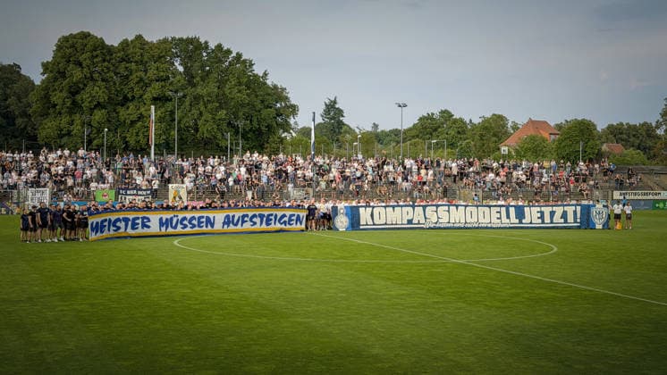 Soccer, Men s, 2026–2027 Season, Northeast Regional League, Matchday 2, SV Babelsberg 03 vs. FC Carl Zeiss Jena, Friday, July 31, 2026, Karl Liebknecht Stadium. Pictured: Fans of SV Babelsberg 03 and FC Carl Zeiss Jena send a clear message on the field at Karl Liebknecht Stadium before the game in support of promotion reform: Champions must be promoted—Compass Model now! Brandenburg, Germany