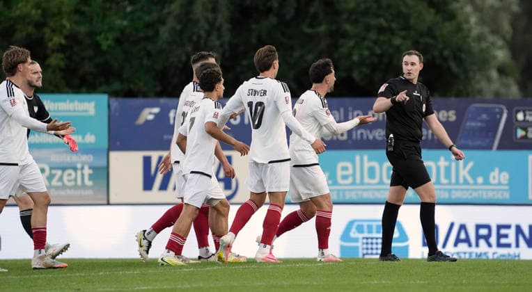 Photo: Jubilation in Drochtersen after Christopher SCHEPP’s crazy arcing shot; here, Phoenix players Fabio Oliveira MAIOLO and Jonathan STÖVER (10) and Benjamin LUIS (24) are protesting against referee Dominik Kopmann. Soccer Regionalliga Nord, Matchday 1 on Fri, July 31, 2026: SV Drochtersen vs. Phönix Lübeck, 2–1