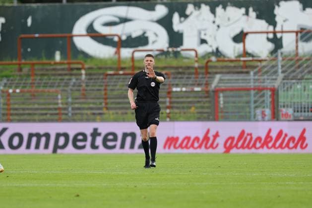 August 26, 2026, GER, Regionalliga Nord, Soccer, Matchday 1, 2026–2027 Season, Dietmar Scholze Stadium at the Lohmuehle, VfB Lübeck vs. SC Weiche Flensburg Individual Action Full-Body Shot Single Subject Cutout Referee Kevin Behrens signals with hand gestures Perimeter advertising Competence brings happiness Photo: nordphoto GmbH Tauchnitz Lübeck Dietmar Scholze Stadium an der Lohmuehle SH Germany Copyright: xnordphotoxGmbHx xTauchnitzx