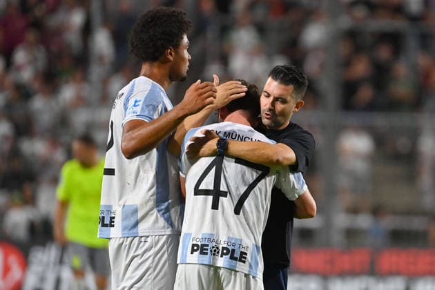 Coach Alper KAYABUNAR of 1860 and Arian Ortivero CALDERON, goalkeeper for TSV 1860 Munich, comfort Lance FIEDLER of TSV 1860 Munich after the game,Consolation, disappointment, frustration, disappointed, frustrated, dejected, Bavarian Regional League soccer season 2026–2027, Matchday 3, TSV 1860 Munich vs. FC Augsburg II, 2–2 on August 7, 2026, at Grünwalder Stadion in Munich