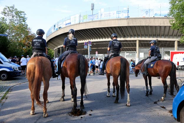 Soccer, Men s, Bavarian Regional League, 2026–2027 Season, TSV 1860 Munich vs. FC Augsburg II, Grünwalder Stadium: Here, a mounted police unit, police horses, police, security match, high-security match, danger, fans, security—with the Westkurve of the Grünwalder Stadium in Munich in the background