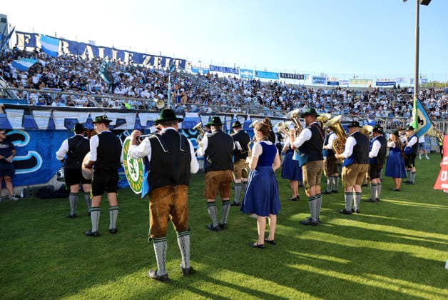 Soccer, Men s, Bavarian Regional League, 2026–2027 Season, TSV 1860 Munich vs. FC Augsburg II, Grünwalder Stadium: The Sechzger Musikanten, a brass band affiliated with TSV 1860 Munich, performing in front of the West Stand
