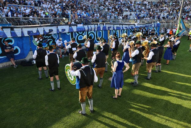 Soccer, Men s, Bavarian Regional League, 2026–2027 Season, TSV 1860 Munich vs. FC Augsburg II, Grünwalder Stadium: The Sechzger Musikanten, a brass band affiliated with TSV 1860 Munich, performing in front of the West Stand