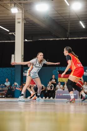 Mia Wiegand 13. Germany is in a defensive stance with her arms outstretched, marking a Montenegrin player. Spectators and a German flag can be seen in the background. Mia Wiegand 13. Germany in a defensive stance against Montenegro Copyright: xJoelxKruehlerx