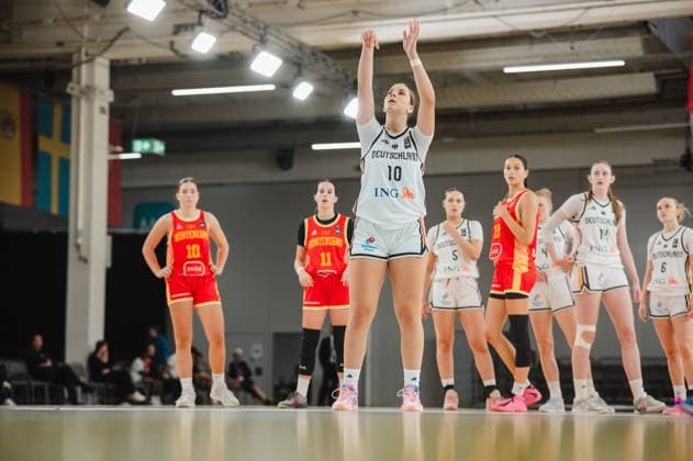 Diana Ivancic, No. 10, Germany, takes a free throw and looks toward the basket with her arms raised. In the background, players from both teams wait for the rebound. Diana Ivancic, No. 10, Germany, taking a free throw against Montenegro Copyright: xJoelxKruehlerx