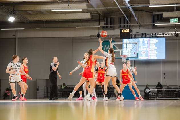 Lara Gierlich of Germany drives toward the basket and shoots over a Montenegrin opponent while the ball is already in the air. The scene shows several players from both teams battling for the rebound at Kistamässan in Stockholm. Lara Gierlich (No. 12, Germany) attempts a shot against Montenegro. Copyright: xJoelxKruehlerx