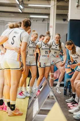The German women s basketball team gathers on the sideline at Kistamässan in Stockholm during a timeout. Frederike Askamp (14, Germany) and Mia Wiegand (13, Germany) are part of the group, who are intently listening to tactical instructions. Frederike Askamp (14) and Mia Wiegand (13) of Germany during a timeout in Stockholm Copyright: xJoelxKruehlerx