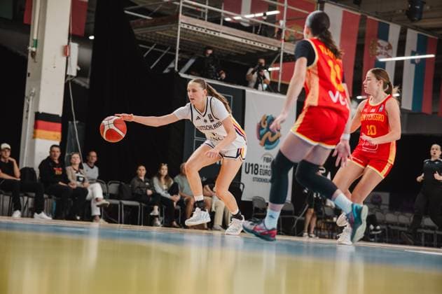 Mia Wiegand 13 of Germany drives the ball into the defensive zone and looks to build an attack against two Montenegrin players. In the background, the FIBA U18 Women’s EuroBasket banner is visible at Kistamässan in Stockholm. Mia Wiegand 13 of Germany dribbles against Montenegro. Copyright: xJoelxKruehlerx