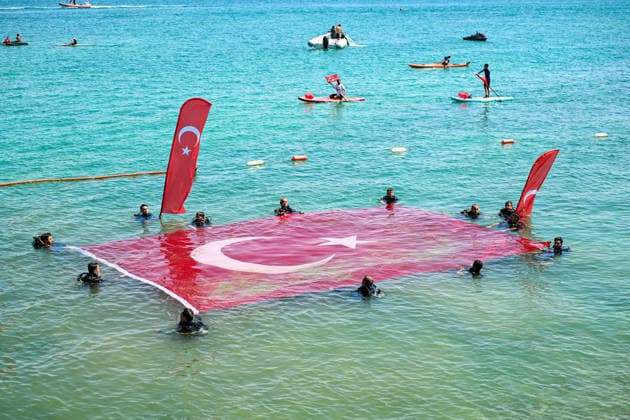 12th Van Sea Water Sports Festival kicks off on Lake Van VAN, TURKIYE - AUGUST 08: An aerial view of divers unfurling a large Turkish flag as participants and athletes taking part in the 12th Van Sea Water Sports Festival held at the Edremit-Gebze Water Sports Center on the shores of Lake Van in Van, Turkiye, on August 08, 2026. Organized to promote Lake Van and boost local tourism, the two-day event features Beach volleyball, Beachvolleyball and handball matches, flyboard demonstrations, canoeing, rowing, dragon boat races, and various recreational activities. Ozkan Bilgin Anadolu Van Turkey. Editorial use only. Please get in touch for any other usage.  Copyright: x2026xAnadoluxOzkanxBilginx