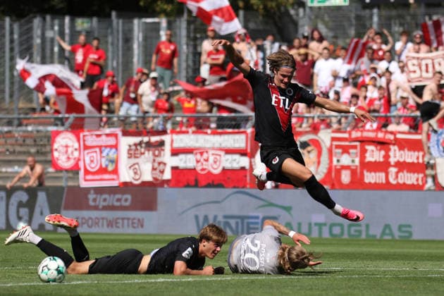 August 8, 2026, xsefx, Soccer, FC Viktoria Köln vs. SSV Jahn Regensburg, 3. Liga, Sportpark Höhenberg, Matchday 1, 2026–2027 Season: Tobias Eisenhuth of FC Viktoria Köln 06 jumps over John Posselt of Jahn Regensburg, who is lying on the ground. DFB regulations prohibit any use of photographs as image sequences and or quasi-video. North Rhine-Westphalia, Germany