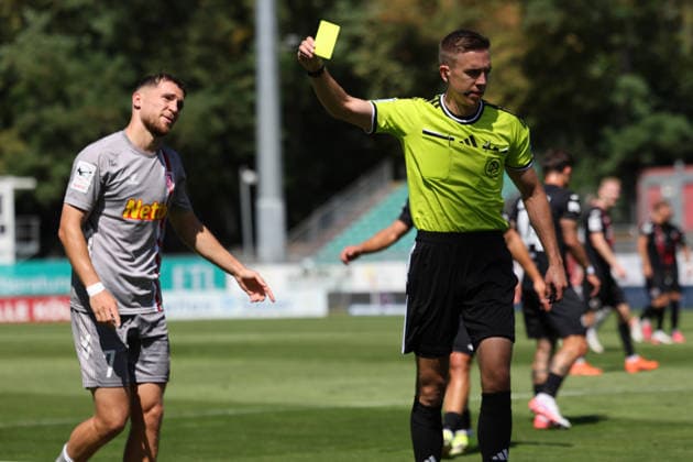 August 8, 2026, xsefx, Soccer, FC Viktoria Köln vs. SSV Jahn Regensburg, 3. Liga, Sportpark Höhenberg, Matchday 1, 2026–2027 Season. Referee Lennart Kernchen shows Oscar Schönfelder of Jahn Regensburg 07 a yellow card. DFB regulations prohibit any use of photographs as image sequences and or quasi-video. North Rhine-Westphalia, Germany