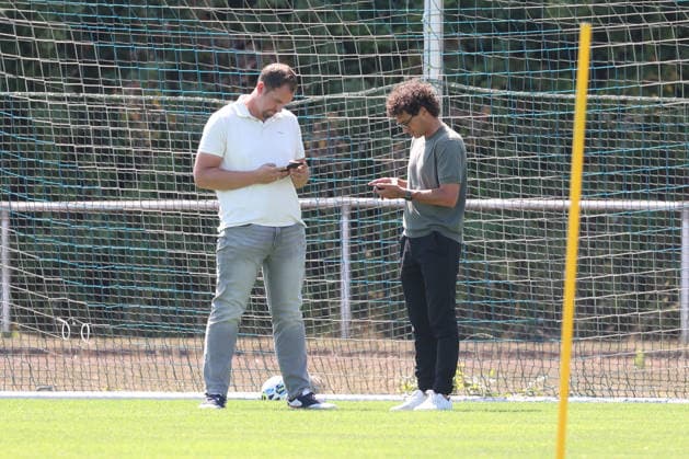 Training session for Sportfreunde Siegen: Managing Director Matthias Georg SI li and Sports Director Nico Michaty SI look at their smartphones. Regional League West soccer, training, Sportfreunde Siegen, on August 10, 2026, in Mudersbach, Germany