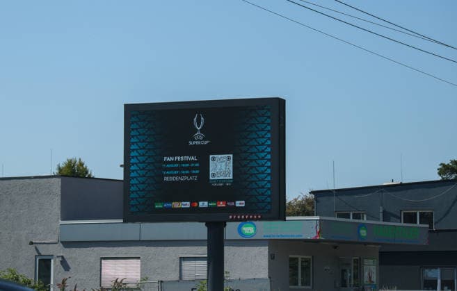 Austria Soccer UEFA Super Cup 2026, Final, Paris Saint-Germain vs. Aston Villa FC, Salzburg: A digital scoreboard in Salzburg promotes the UEFA Super Cup Fan Festival with event times and a QR code. The photo was taken on the day of the 2026 UEFA Super Cup Final between Paris Saint-Germain and Aston Villa FC and shows the event signage throughout the city before kickoff. Copyright: xAymanxAlahmedx
