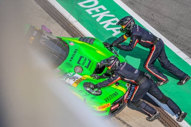 Two Manthey Racing mechanics push the neon-green Porsche 911 GT3 R 90, with Ricardo Feller at the wheel, down the pit lane at the Nürburgring. The bird s-eye view shows the pit stop in progress, with DEKRA written on the asphalt. Porsche 911 GT3 R 90 from Manthey Racing during a pit stop at the Nürburgring Copyright: xMichaelxSchäferx