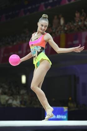 A gymnast performs a ball routine at the 2026 Rhythmic Gymnastics World Championships in Frankfurt’s Festhalle, balancing on one leg. The pink ball is at hip level, her face shows concentration and a slight smile. 2026 Rhythmic Gymnastics World Championships – Ball routine at the Festhalle in Frankfurt Copyright: xspeedshotx
