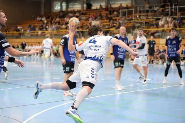 Paul Holzhacker 4 of VfL Lübeck Schwartau takes off in a dynamic jump shot motion, the ball already in his shooting hand. Several players from Grindstedt GIF watch the action in the background. Paul Holzhacker 4 of VfL Lübeck Schwartau takes a jump shot. Copyright: xspeedshotx