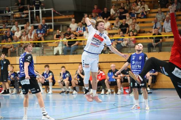 Magnus Holpert, 22, of VfL Lübeck Schwartau, jumps high and takes a shot, while Anders Toft (No. 8, Grindstedt GIF) watches the play. In the background, numerous spectators watch the game at the Hansehalle in Lübeck. Magnus Holpert (No. 22, VfL Lübeck Schwartau) takes a jump shot at the Hansehalle. Copyright: xspeedshotx