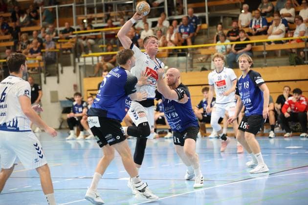 Ole Hagedorn of VfL Lübeck Schwartau jumps to take a shot while being pressured by Kristoffer Jessen of Grindstedt GIF. In the background, other players from both teams can be seen, as well as the packed stands at the Hansehalle in Lübeck. Ole Hagedorn of VfL Lübeck Schwartau takes a shot against Grindstedt GIF Copyright: xspeedshotx