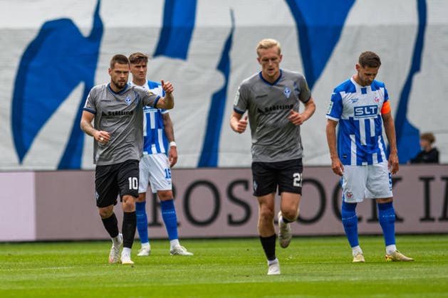 Rostock, Germany, August 16, 2026, 3rd League 2026–2027, Matchday 2: FC Hansa Rostock vs. SV Waldhof Mannheim. Pictured, 1st from left: Julian Ulbricht of Waldhof Mannheim celebrates after scoring the 0–1 goal, gesturing on the field; 1st from right: Marco Schuster of Hansa Rostock looks down at the ground, looking dissatisfied Copyright: xFotostandx xVoelkerx