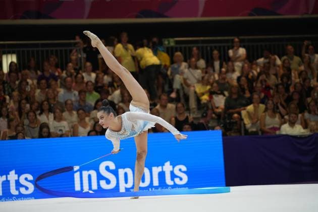 Alina Harnasko performs a balancing pose with her leg extended and a ribbon at the Festhalle in Frankfurt. The audience watches the routine at the 2026 World Championships in Rhythmic Gymnastics. Rhythmic Gymnastics – Gymnast with a ribbon at the World Championships in Frankfurt Copyright: xspeedshotx