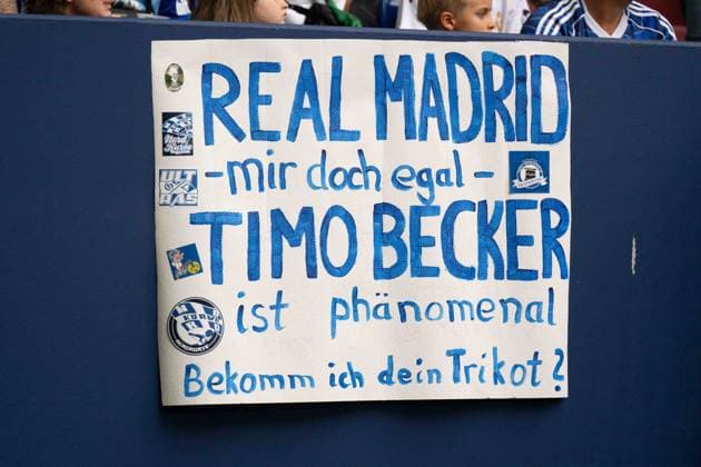 August 16, 2026: Soccer – FC Schalke 04 vs. Real Madrid, friendly match at the Veltins Arena in Gelsenkirchen; Schalke 04 fans holding a sign; Timo Becker, Schalke 04, 5 IMPORTANT NOTICE: In accordance with the regulations of the DFL and the DFB, it is prohibited to use or allow the use of photographs taken in the stadium and or during the game in the form of sequential images and or video-like photo series. Copyright: xJamesxZabelx