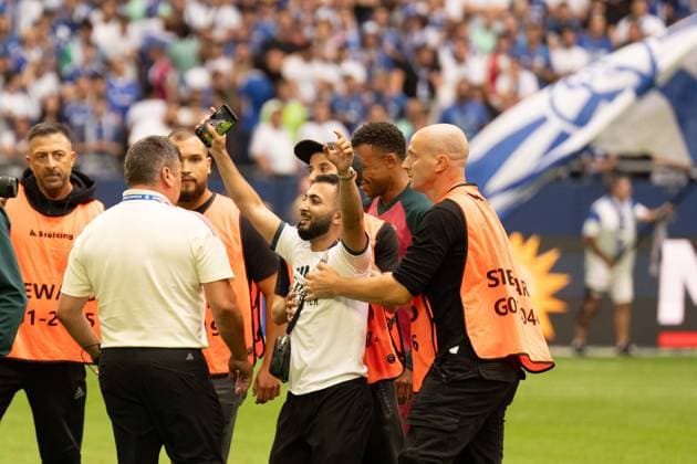 August 16, 2026: Soccer – FC Schalke 04 vs. Real Madrid, friendly match at the Veltins Arena in Gelsenkirchen. A Real Madrid fan runs onto the field after the kickoff to take a selfie with Kylian Mbappé of Real Madrid, 10 and is intercepted by security after the selfie and escorted off the field IMPORTANT NOTICE In accordance with the guidelines of the DFL and the DFB, it is prohibited to to use or allow the use of photographs taken in the stadium and or during the game in the form of sequential images and or video-like photo series Copyright: xJamesxZabelx