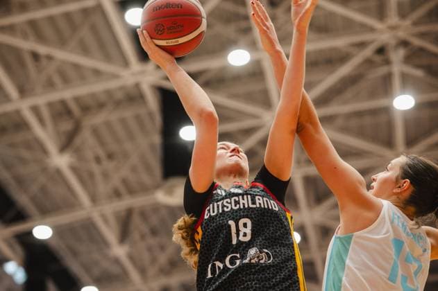 Nele Prowaznik, 18, of Team Germany U16W 2026, drives toward the basket and is blocked by a Slovenian player. The Molten basketball is clearly visible in the shot, and the low-angle shot emphasizes the dynamism of the scene. Nele Prowaznik, No. 18, Germany U16 Women, shooting for the basket against Slovenia Copyright: xJoelxKruehlerx