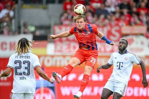 Sacha Boey of FC Bayern Munich, Mikkel Kaufmann of 1. FC Heidenheim 1846, and Dayot Upamecano of FC Bayern Munich battle for the ball during the preseason friendly match between 1. FC Heidenheim and FC Bayern Munich at the Voith Arena on August 18, 2026 in Heidenheim, Germany. Photo by Harry Langer, DeFodi Images