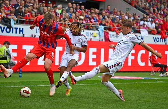 August 18, 2026, 2026–2027 Bundesliga, Friendly Match, 1. FC Heidenheim vs. FC Bayern Munich, at the Voith Arena in Heidenheim; from left: Julian Niehues (1. FC Heidenheim 1846), Sacha Boey (FC Bayern Munich), and Tim Binder (FC Bayern Munich)