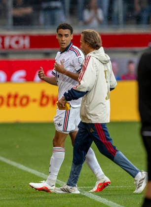 August 18, 2026, 2026–2027 Bundesliga season, friendly match, 1. FC Heidenheim vs. FC Bayern Munich, at the Voith Arena in Heidenheim; after collapsing again during the game, Jamal Musiala (left), of Bayern Munich, is treated by team doctor Prof. Dr. Peter Ueblacker and led off the field