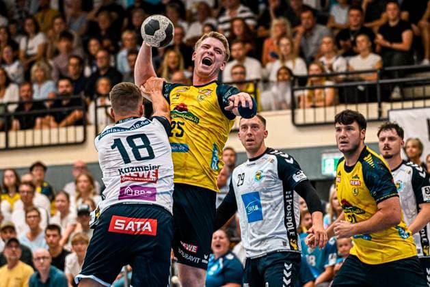 Haukur Thrastarson (25, Rhein Neckar Löwen) leaps up to shoot during a one-on-one battle with Felix Kazmeier (18, SV Salamander Kornwestheim) and holds the ball above his head. In the background, Jan Döll (29, SV Salamander Kornwestheim) and other players from both teams watch the action in the packed Sporthalle Ost in Kornwestheim. Haukur Thrastarson (25) of the Rhein Neckar Löwen rises to take a shot Copyright: xspeedshotx xDorianfrickx