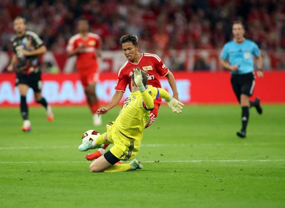 Soccer, Men s, Bundesliga, 2026–2027 Season, FC Bayern Munich vs. 1. FC Union Berlin, Allianz Arena: Manuel Neuer of FC Bayern Munich clears the ball at the last second with a sliding tackle in front of Woo Yeong Jeong of 1. FC Union Berlin. DFB and DFL regulations prohibit any use of photographs as image sequences and or quasi-video.