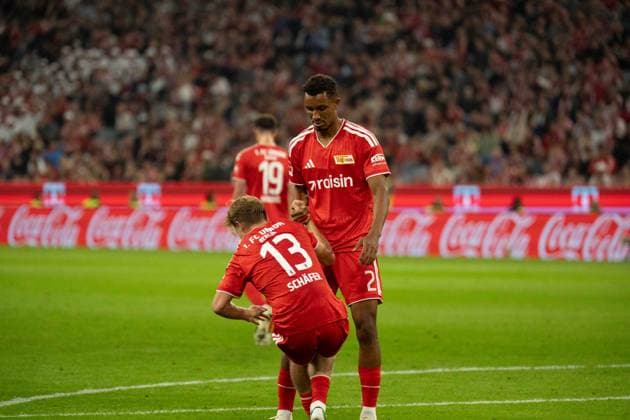 September 18, 2026: FC Bayern Munich vs. Union Berlin, Matchday 4 of the Bundesliga at the Allianz Arena in Munich. Felix Uduokhai (Union Berlin, No. 2) assists Andras Schafer (Union Berlin), 13 stand up IMPORTANT NOTICE: In accordance with DFL and DFB regulations, it is prohibited to use or allow the use of photographs taken in the stadium and or during the game in the form of sequential images and or video-like photo series. Copyright: xJamesxZabelx