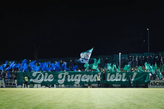 September 18, 2026, xkwix, Soccer, Regionalliga West, SV Rödinghausen vs. FC Gütersloh, Häcker Wiehenstadion, Matchday 9, 2026–2027 season: Gütersloh fans with banners and flags in the visitors section. DFB regulations prohibit any use of photographs as image sequences and or quasi-video. Photo: xKamilxWilkowskixPressefotoKochx, North Rhine-Westphalia, Germany