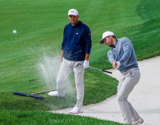 Scottie Scheffler of the US (L) watches as Sam Burns of the US hits from a sand trap by the twelfth green during practice for the Presidents Cup golf tournament at Medinah Country Club in Medinah, Illinois on Tuesday, September 22, 2026. Competition between the USA and the International team begins on Thursday, September 24 with Four-Ball play.  MED20260922902 TANNENxMAURY