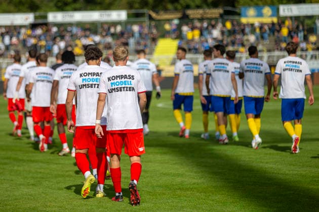 GER, Leipzig, Soccer, Northeast Regional League, Matchday 11, 1 FC Lokomotive Leipzig vs. FC Rot Weiß Erfurt: In the photo (from left), the teams are running into the stadium wearing T-shirts supporting the 3. Liga promotion reform, with the slogan Implement the Compass Model and a protest against the promotion regulations dated September 26, 2026, Bruno Plache Stadium, Leipzig. DFB regulations prohibit any use of photographs as image sequences and or quasi-video, Copyright: HMBxMedia PaulxFritz