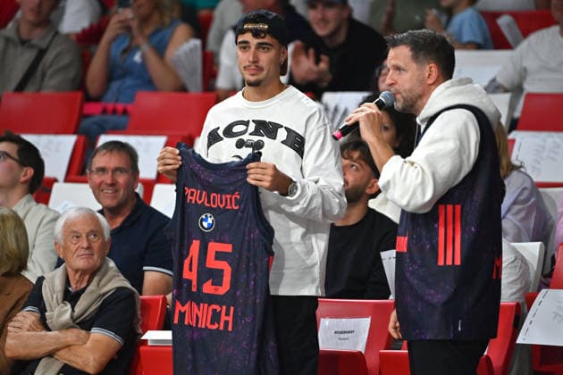 Aleksandar PAVLOVIC of Bayern Munich, sitting in the stands, is presented with a basketball jersey. BBL, 2026–2027 season: FC Bayern Munich vs. Alba Berlin on September 26, 2026, at BMW Park