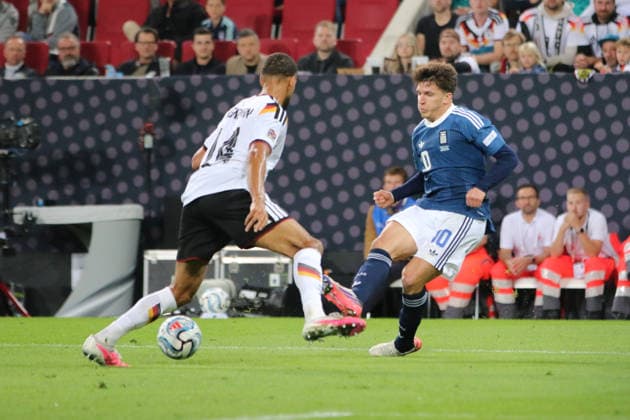 September 27, 2026 Men s Soccer 2026–2027 UEFA Nations League Matchday 2 Germany vs. Greece WWK Arena, Augsburg Christos Tzolis (Greece, No. 10, blue) plays a pass; Josha Vagnoman (Germany, No. 14, white) watches the play Augsburg, Bavaria, Germany