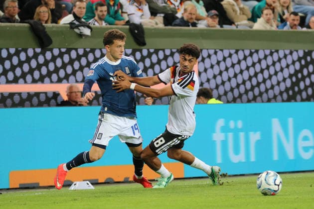 September 27, 2026 Men s Soccer 2026–2027 UEFA Nations League Matchday 2 Germany vs. Greece WWK Arena, Augsburg Nathaniel Brown (Germany, 18, in white) in a tackle with Konstantinos Karetsas (Greece, 19, in blue) Augsburg, Bavaria, Germany