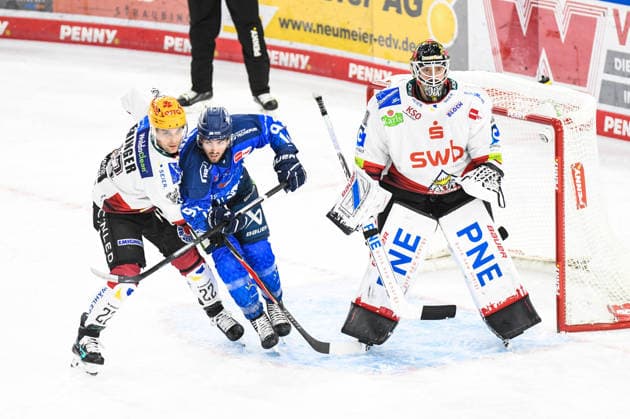 Spencer Kersten of the Straubing Tigers in front of the net with Vladimir Eminger and Kristers Gudlevskis of the Bremerhaven Pinguins, Men s Ice Hockey, German Ice Hockey League, Penny DEL, Matchday 5, 2026–2027 season on October 2, 2026, at the Eisstadion am Pulverturm; Straubing Tigers (blue) vs. Pinguins Bremerhaven (white)
