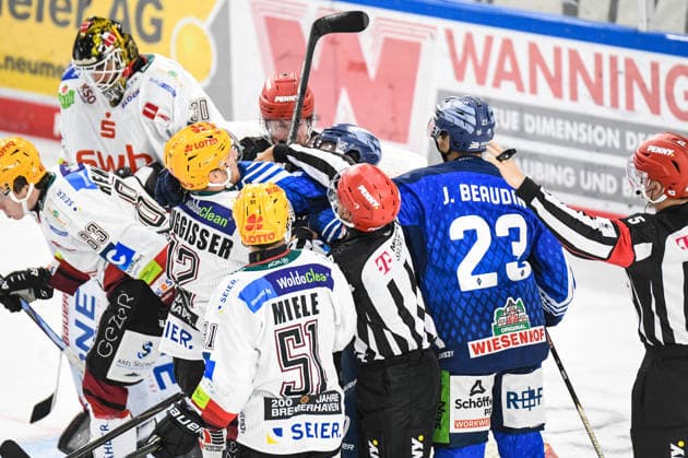 Jamieson Rees and J. C. Beaudin of the Straubing Tigers in a scuffle with Phillip Bruggisser of the Bremerhaven Pinguins, Men s Ice Hockey, German Ice Hockey League, Penny DEL, Matchday 5, 2026–2027 season on October 2, 2026, at the Eisstadion am Pulverturm, Straubing Tigers (blue) vs. Pinguins Bremerhaven (white)