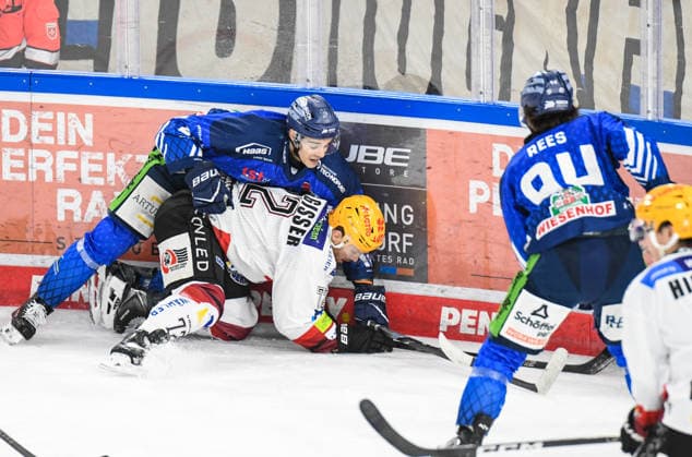 J. C. Beaudin of the Straubing Tigers at the boards with Phillip Bruggisser of the Bremerhaven Pinguins, Men s Ice Hockey, German Ice Hockey League, Penny DEL, Matchday 5, 2026–2027 season on October 2, 2026, at the Eisstadion am Pulverturm; Straubing Tigers (blue) vs. Pinguins Bremerhaven (white)