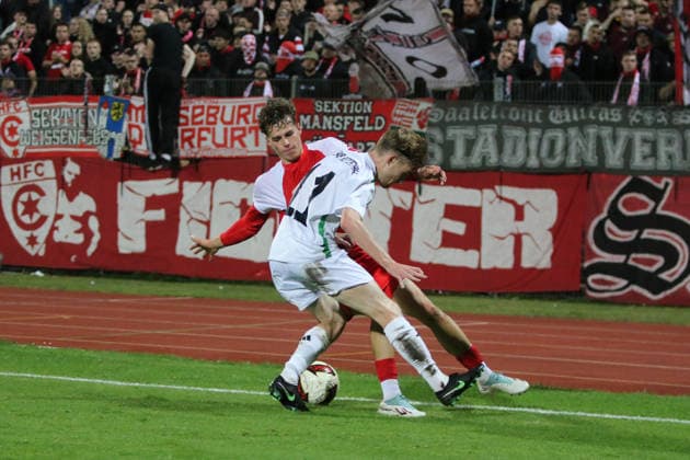 October 2, 2026 Men s Soccer 2026–2027 dachbleche24 State Cup, 2nd Round: SG Reppichau vs. Hallescher FC at Paul Greifzu Stadium, Dessau-Roßlau, Romeo Trinko Hall, 19, in red, in a tackle with Franz Töpfer (Reppichau), 11, in white; Dessau-Roßlau, Saxony-Anhalt, Germany