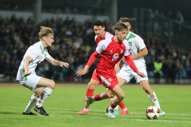 October 2, 2026 Men s Soccer 2026–2027 dachbleche24 State Cup, 2nd Round: SG Reppichau vs. Hallescher FC at Paul Greifzu Stadium, Dessau-Roßlau; Felix Langhammer, Halle, 34, in red, positions the ball; Franz Töpfer of Reppichau, 11, in white, arrives too late; Dessau-Roßlau, Saxony-Anhalt, Germany