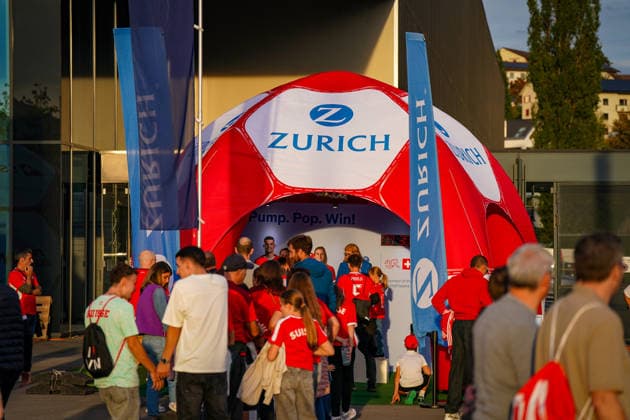 Soccer: UEFA Nations League 2026–2027, Matchday 3: Switzerland vs. Slovenia at Swissporarena in Lucerne. Fans outside the Swissporarena in Lucerne at a promotional booth set up by the insurance company Zurich ahead of the international match between Switzerland and Slovenia. An inflatable soccer ball serves as a promotional item; many visitors are wearing Swiss fan apparel. Zurich, Zurich Insurance, insurance, sponsor, sponsorship, advertising, promotional materials, promotion, fan zone, fans, spectators, Switzerland, Slovenia, soccer, international match, Swissporarena, Lucerne, business Copyright: xJOERANxSTEINSIEKx