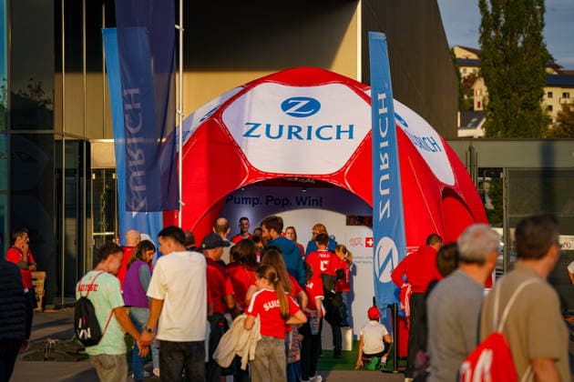 Soccer: UEFA Nations League 2026–2027, Matchday 3: Switzerland vs. Slovenia at Swissporarena in Lucerne. Fans outside the Swissporarena in Lucerne at a promotional booth set up by the insurance company Zurich ahead of the international match between Switzerland and Slovenia. An inflatable soccer ball serves as a promotional item; many visitors are wearing Swiss fan apparel. Zurich, Zurich Insurance, insurance, sponsor, sponsorship, advertising, promotional materials, promotion, fan zone, fans, spectators, Switzerland, Slovenia, soccer, international match, Swissporarena, Lucerne, business Copyright: xJOERANxSTEINSIEKx