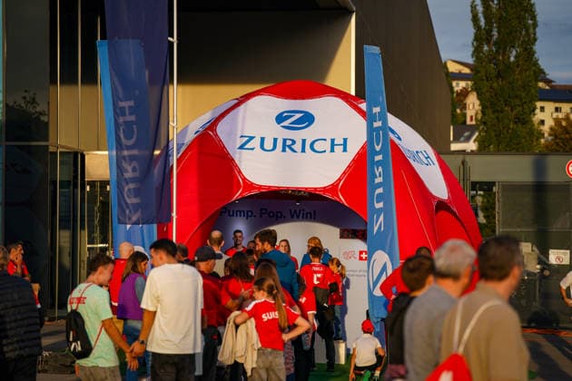 Soccer: UEFA Nations League 2026–2027, Matchday 3: Switzerland vs. Slovenia at Swissporarena in Lucerne. Fans outside the Swissporarena in Lucerne at a promotional booth set up by the insurance company Zurich ahead of the international match between Switzerland and Slovenia. An inflatable soccer ball serves as a promotional item; many visitors are wearing Swiss fan apparel. Zurich, Zurich Insurance, insurance, sponsor, sponsorship, advertising, promotional materials, promotion, fan zone, fans, spectators, Switzerland, Slovenia, soccer, international match, Swissporarena, Lucerne, business Copyright: xJOERANxSTEINSIEKx