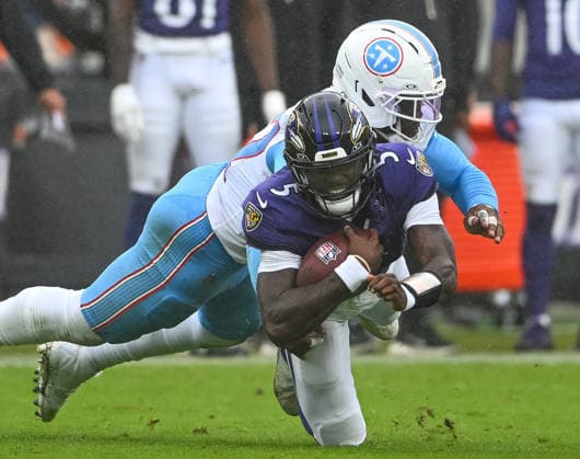 Baltimore Ravens quarterback Tyler Huntley (5) earns an 8 yard gain before Tennessee Titans defensive end Jacob Martin (57) tackles him during the fourth quarter at M&T Bank Stadium in Baltimore, Maryland, on Sunday, October 4, 2026. Baltimore won 24-18.  BAL20261004115 DAVIDxTULIS