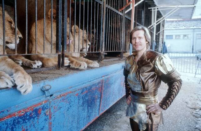 Sigmar Solbach (Schauspieler) 12 85 wie Sigmar Solbach im Dezember 1985 bei Stars in der Manege (BR) Circus Krone Zirkus Deutschland deutsch Deutscher Mann Fernsehen TV Schauspiel german actor quer halb stehend draußen neutral blond leger Schnurrbart Schnäuzer Oberlippenbart Bart Löwe Löwenkäfig