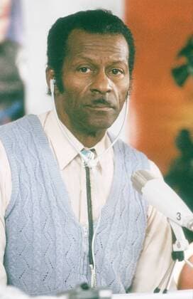 Chuck Berry (Musiker) 02 88 köh Mann Musik Blues Jazz Pop USA Amerika dunkelhäutig dunkelhaarig Locken Bart leger Hemd Weste gestreift sitzend Tisch Mikrophon Kopfhörer Portrait hoch neutral